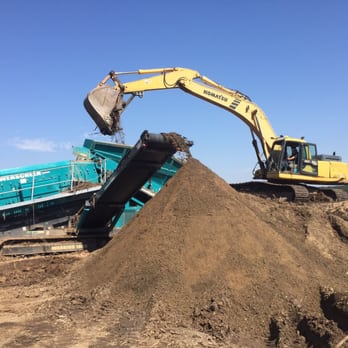 Excavator loading dirt into a machine on a construction site