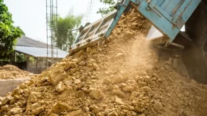 Construction site with compactable fill dirt being delivered and leveled for grading and backfill.